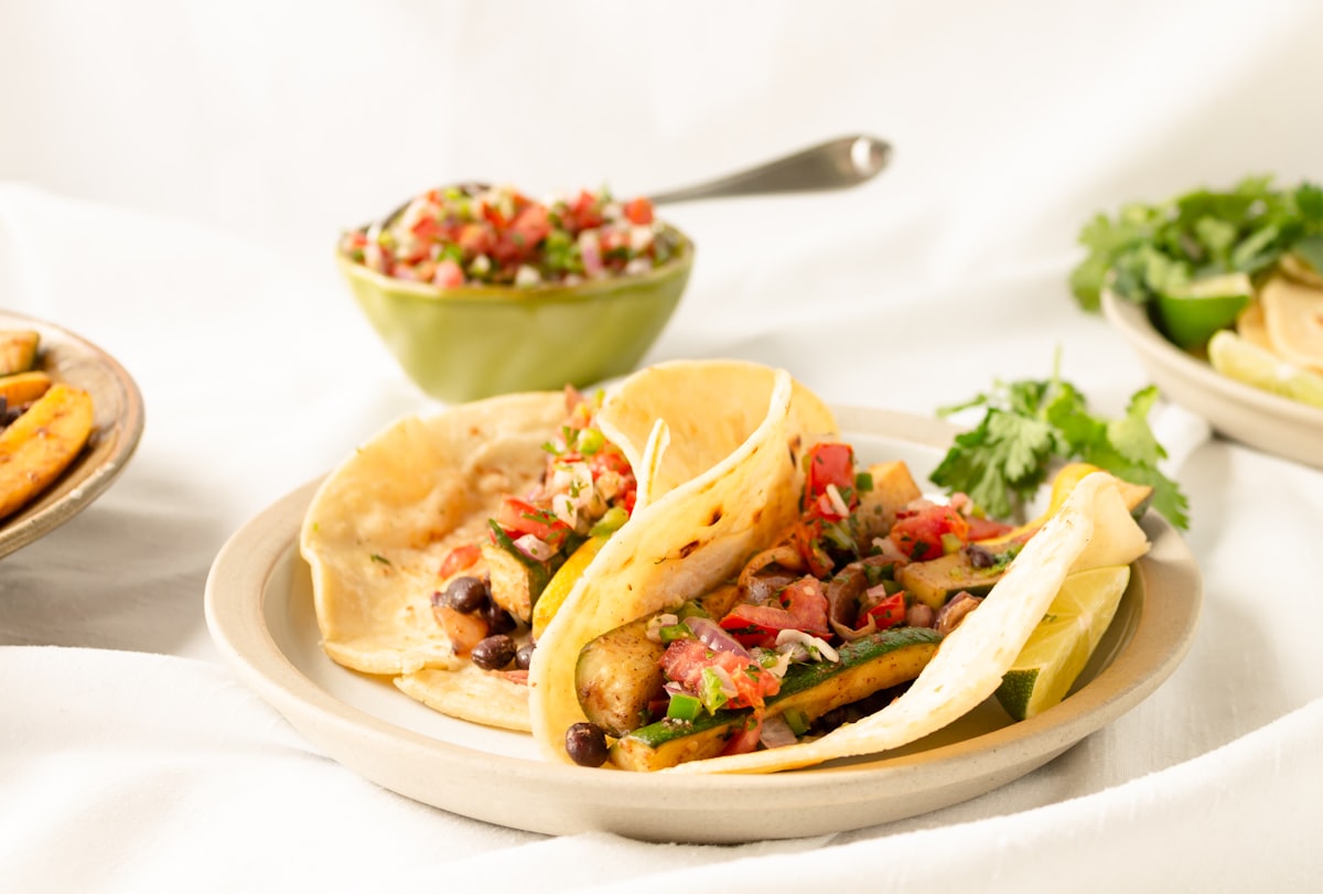 Black bean tacos on soft corn tortillas with salsa, coriander and lime