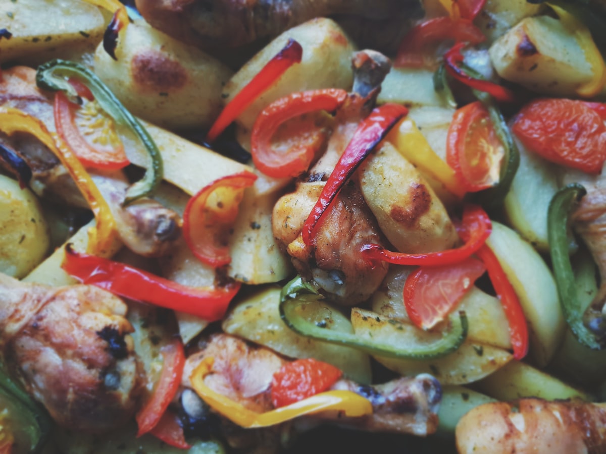 Roast chicken with peppers and potatoes in a tray, ready to be pulled for sandwiches
