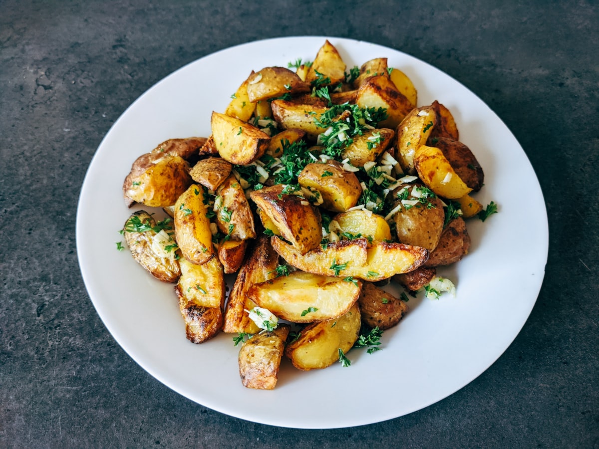 Crushed potatoes fried crisp, scattered with parsley and garlic, on a white plate